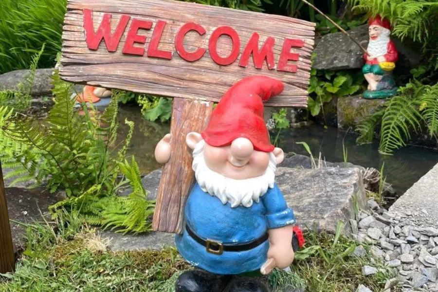 A gnome at the The Gnome Reserve holding a welcome sign